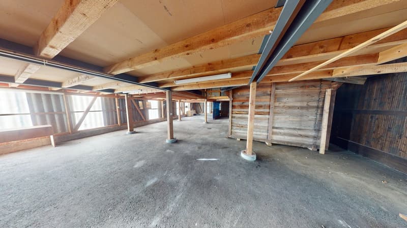 Wide interior, wooden beams, concrete floor, open windows, long wooden bench, concrete pillars