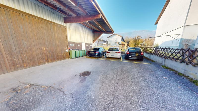 large car park with three cars parked, yellow parking lines, three bins