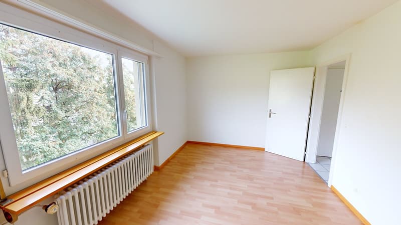 empty room, wooden floor, white walls, large window, radiator, two doors