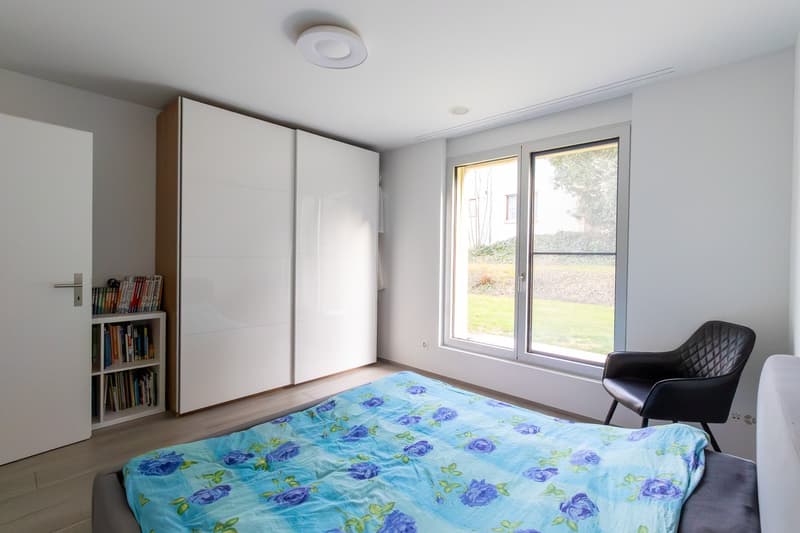 bedroom with bed, white wardrobe, bookshelf, window, chair