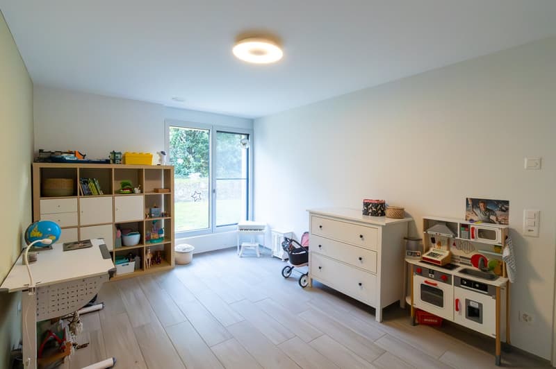 A room with a desk, a cabinet, a toy kitchen, a stroller, a globe, and a window.