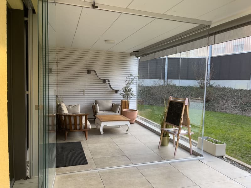 glass walls, wooden chairs, white table, potted plants, blackboard, rug