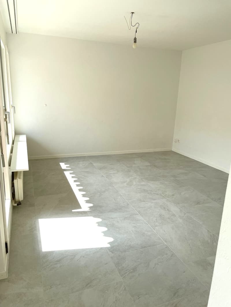 empty room, white walls, gray tiles, window, radiator, power outlets