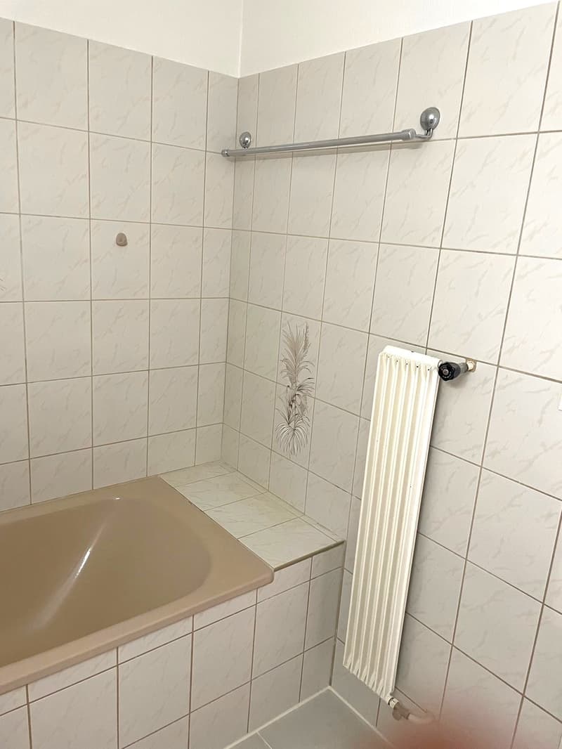 Bathroom with bathtub, white tiles, towel rack, radiator