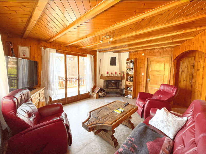 wooden walls, fireplace, red leather chairs, wooden coffee table, TV, wooden shelves