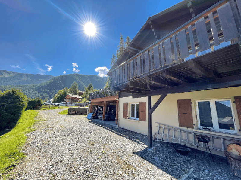 Mountain house, wooden balcony, gravel driveway, garage, mountain view