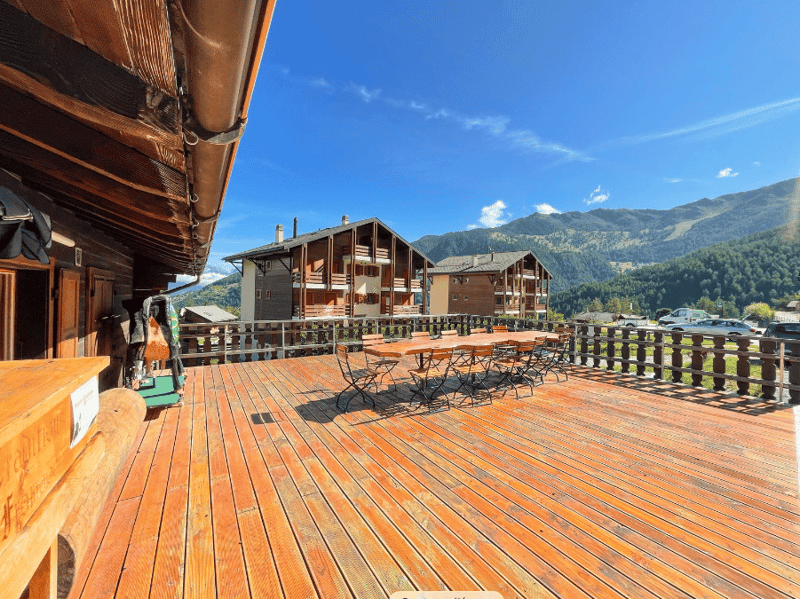 wooden deck, wooden railing, dining table, chairs, mountains in the background
