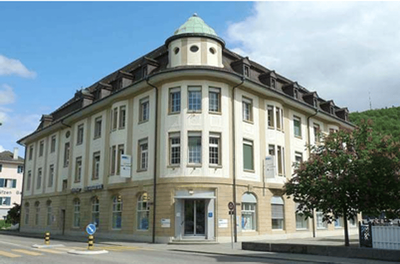 3 story building, many windows, curved roof, entrance at the front