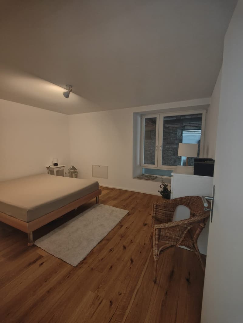 bedroom with bed, rug, chair, window, lamp, side table, ceiling lamp