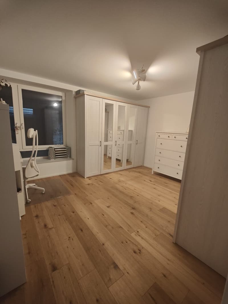 Empty room with wooden floor, white walls, large window, white office chair, white wardrobe, white dresser