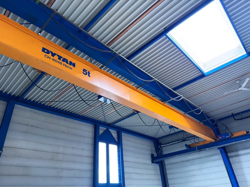 large yellow crane with blue trim, metal ceiling, metal walls, large skylight