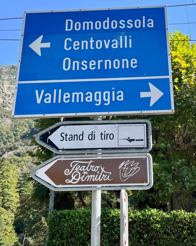 Directional road signs pointing to Domodossola, Centrovalli, Onsernone, and Vallemaggia with a lower sign for Stand di tiro (shooting range)