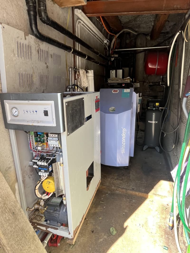 A utility room with HVAC systems, a large air tank, and several pipes.
