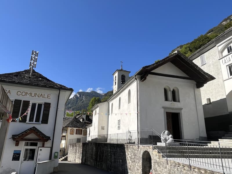 stone house, white stucco, slate roof, church in the background, mountains in the distance