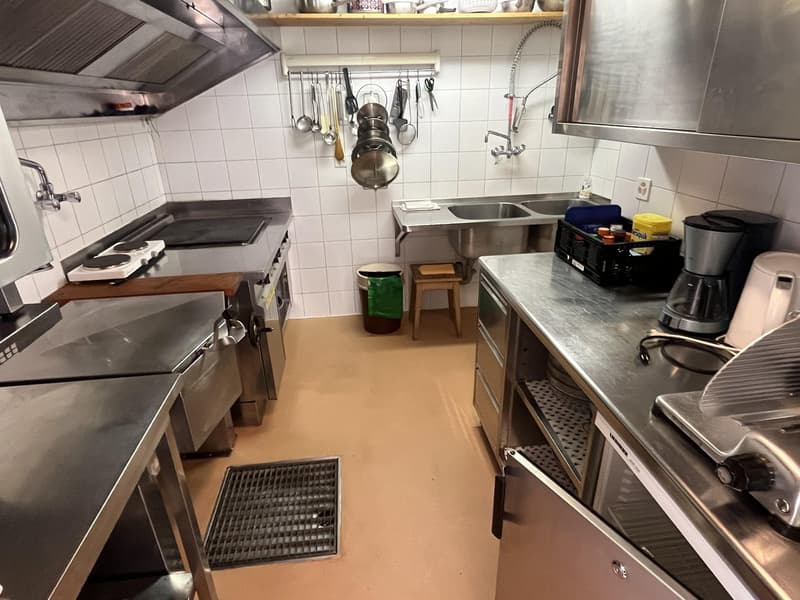 Stainless steel countertops, double stainless steel sinks, multiple kitchen appliances including a stove, griddle, coffee maker, and trash bins