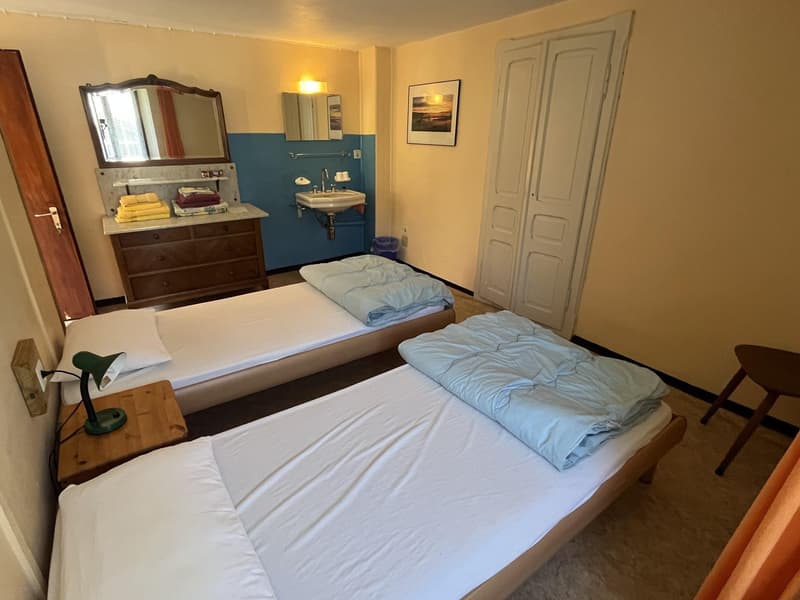 Two single beds, bedside tables with lamps, wooden wardrobe, mirror, sink, picture frame