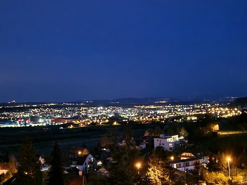night aerial view of the city with buildings, hills, and mountain in the distance
