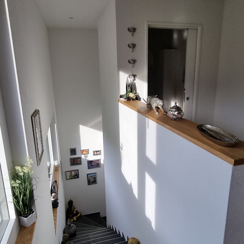 Interior view, white walls, concrete stairs, wooden shelf, photo frames on wall, decorative items