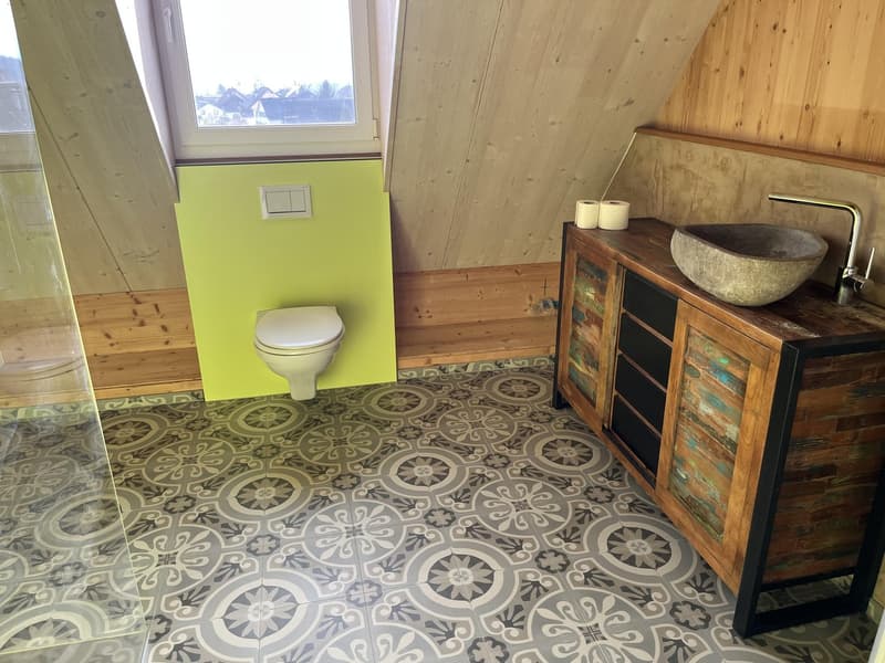 Modern bathroom with wooden cabinet, sink, and toilet