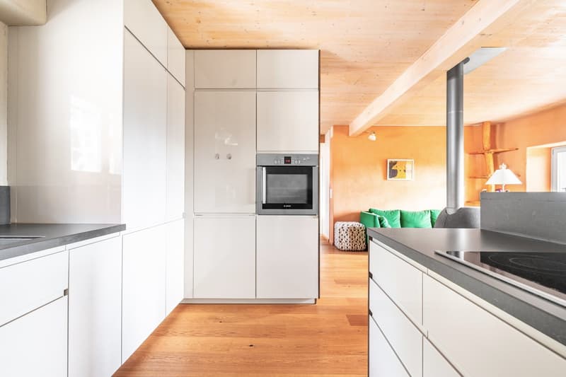 modern minimalist kitchen with wooden floor, white cabinets, stainless steel appliances, and a sleek granite countertop