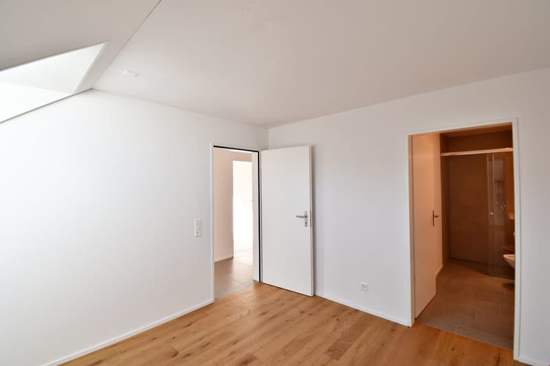 empty room, wooden floor, white walls, two doors, one leading to a bathroom, another to another room