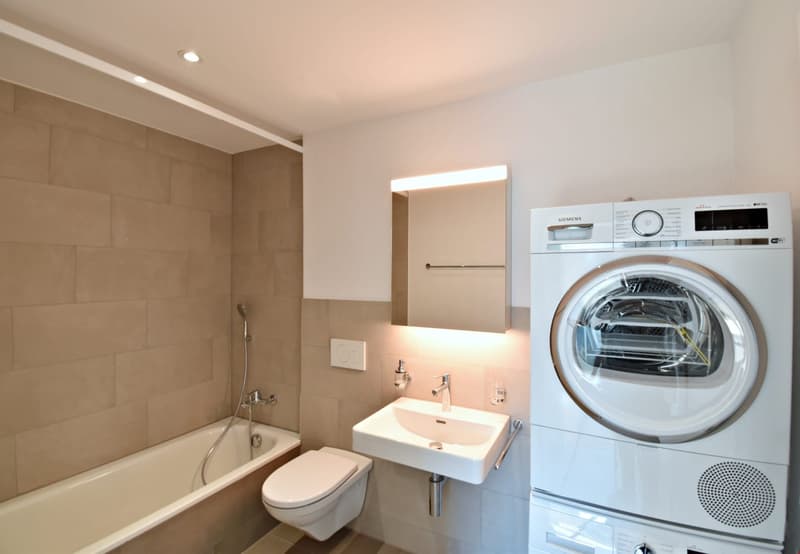 Bathroom with bathtub, toilet, sink, and washing machine