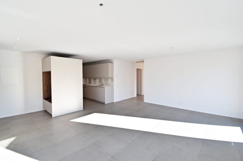 Empty room with white walls, gray tiles, kitchen with sink and faucet, and a white cabinet.