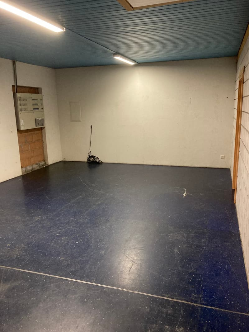 Empty room, white walls, ceiling lights, blue floor, outlet