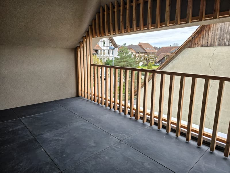 Balcony with wooden railing, black tiled floor, view of the street and houses