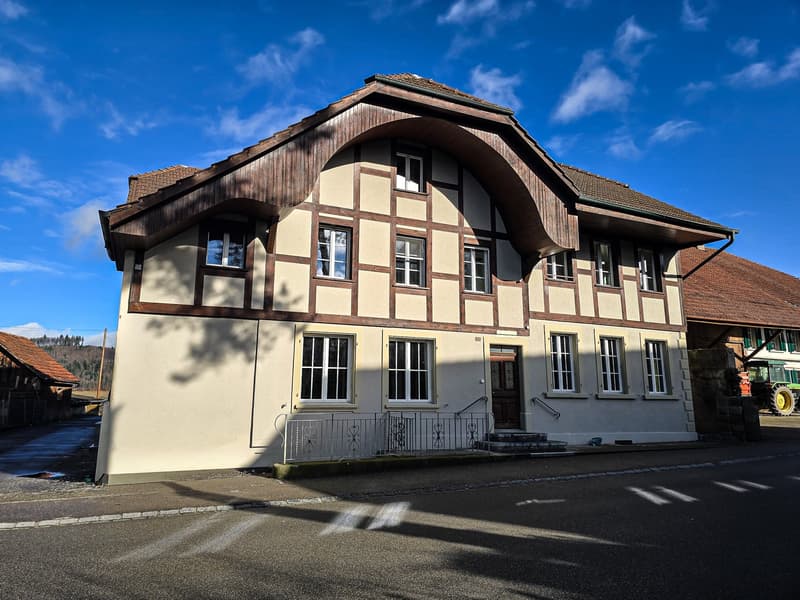 2 story house, brown roof, beige walls, wooden trim, multiple windows, front door, steps leading up to the entrance, metal railings