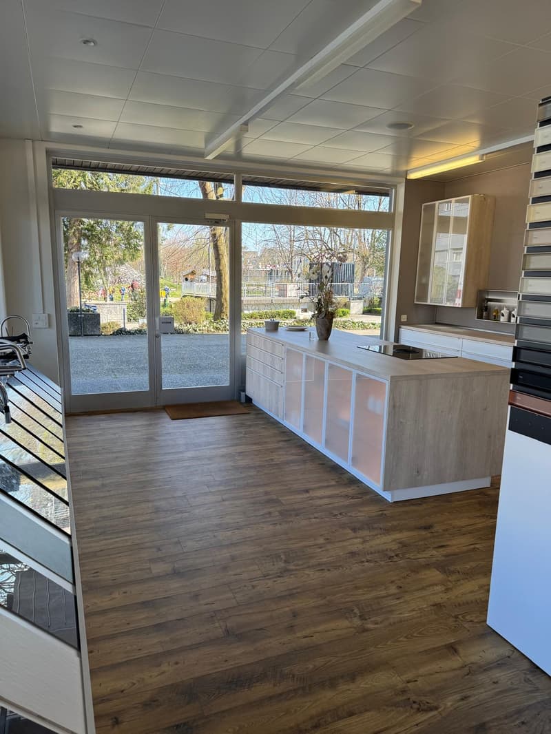 Open kitchen with large windows, wooden floor, modern cabinets, island with stove, and a view of the outside