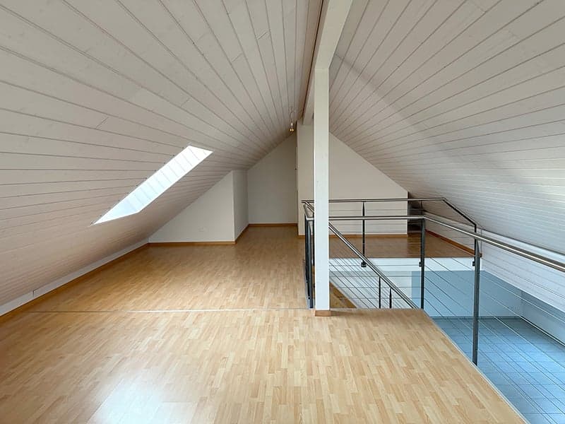 empty attic room, wooden floor, white ceiling, metal railing, skylight