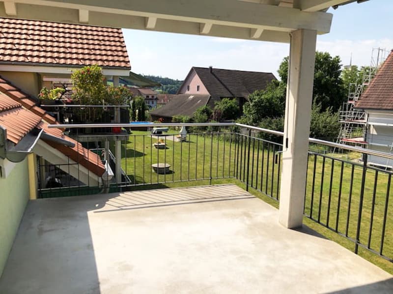 covered balcony with metal railings, overlooking a grassy yard with a pool