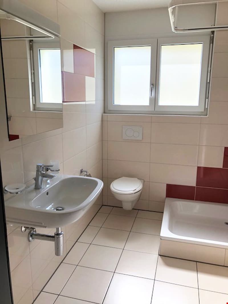 Bathroom with white tiles, white sink, white toilet, bathtub, mirror, and windows