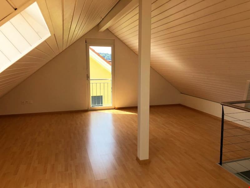 empty attic room with wooden floor, glass door, and window with balcony
