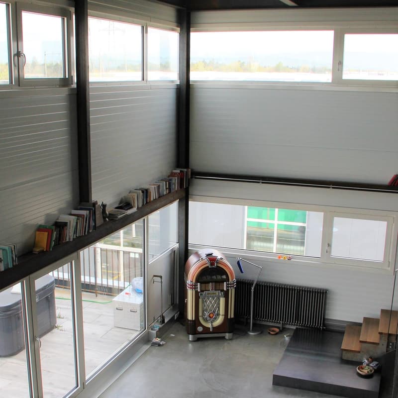 large windows, open space, books on shelf, vintage jukebox, radiator, wooden stairs