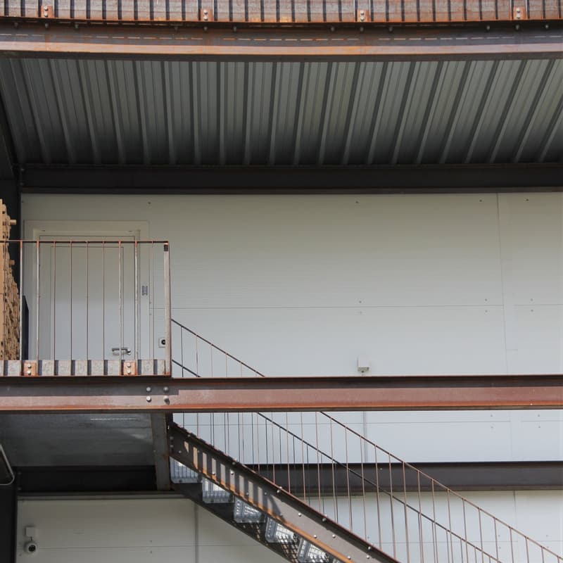 Metal railings, metal stairs, metal ceiling, white walls, door