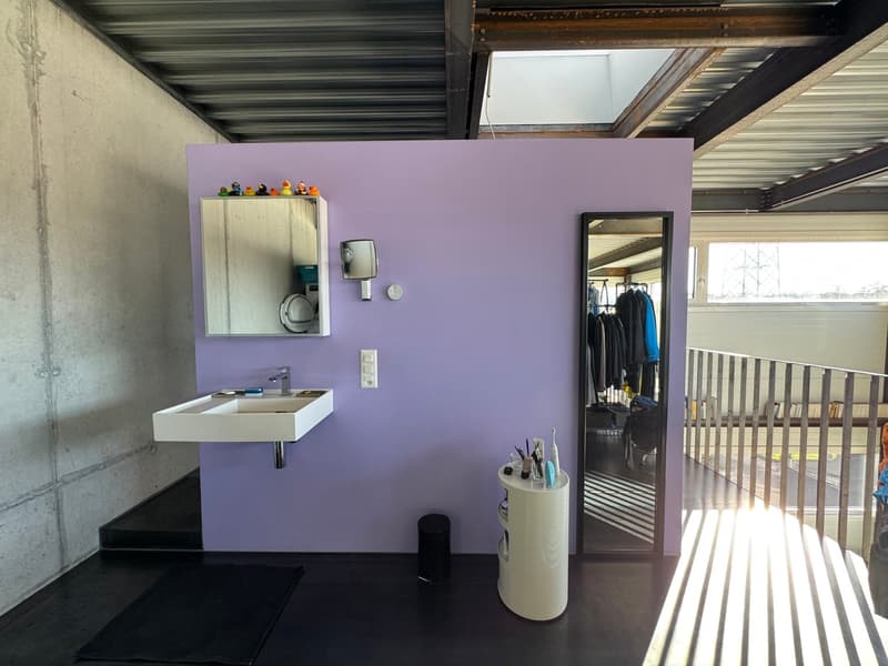 Bathroom with purple wall, white sink, mirror, trash bin, and a small table with toiletries