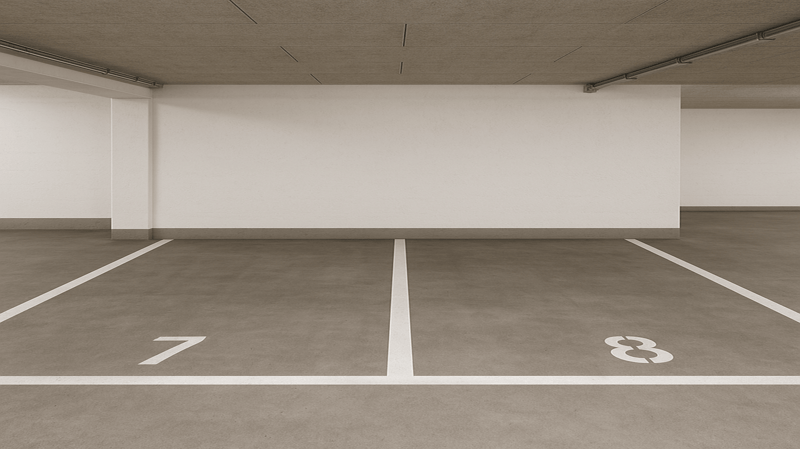 Empty parking lot with parking spaces marked, concrete flooring, white walls, and ceiling