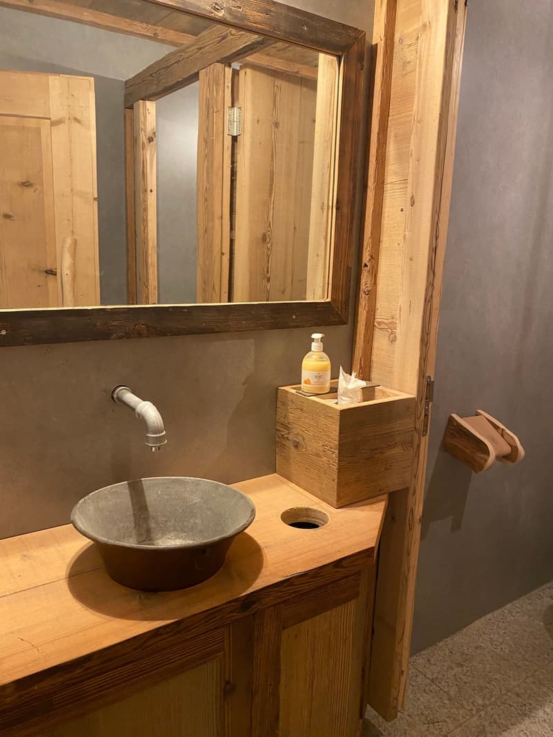 Bathroom with wooden walls, concrete sink, wooden mirror, wooden storage box, wooden toilet paper holder