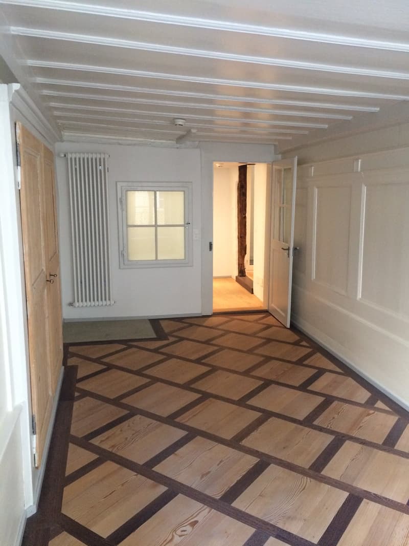 long hallway, wooden floor, radiator, wooden doors, white walls