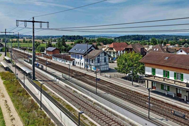 Aerial view of a small town with a train station, houses, and a railway track.