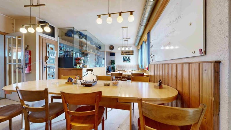Dining room with wooden table, chairs, and a whiteboard on the wall