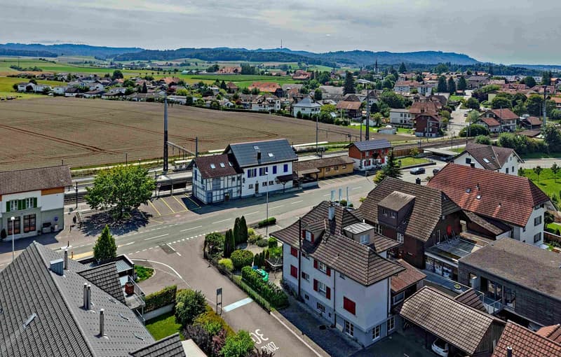 Aerial view of a town with houses, a road, a field, and mountains in the background