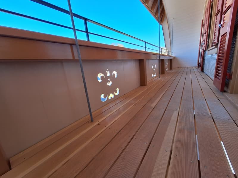 wooden floor, metal railing, decorative wall patterns, large windows