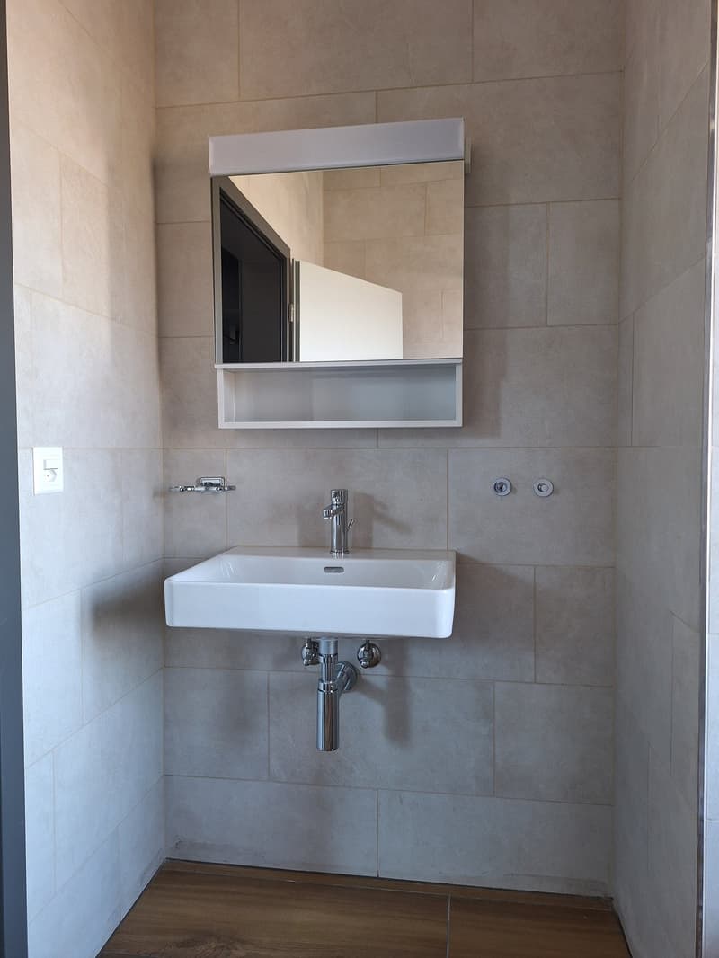 Bathroom with white sink, mirror, and tiled walls