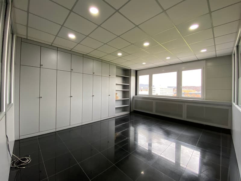 Empty room with white cabinets, tiled floor, large windows, panelled sills, and a view of the outside