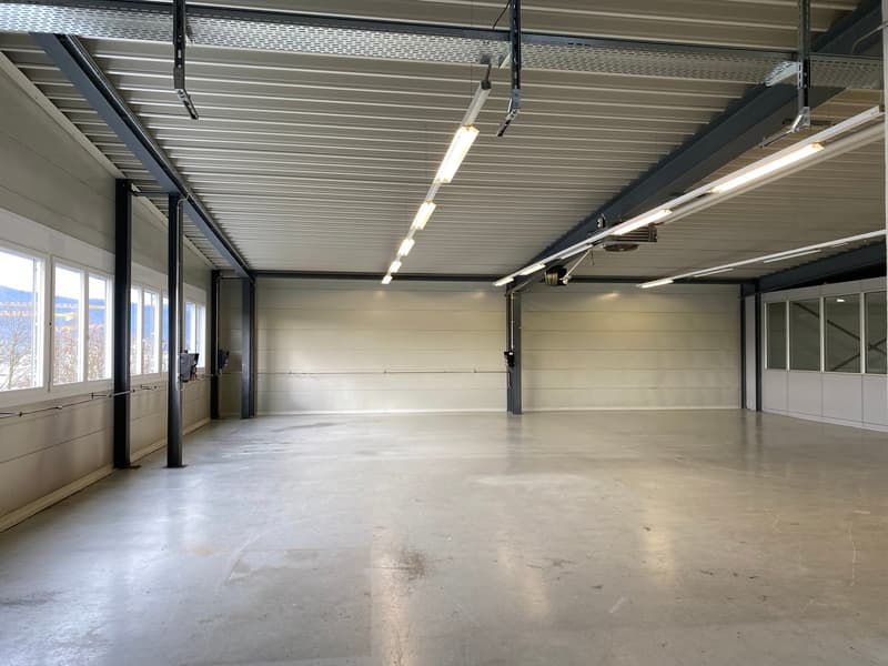 Empty room with concrete floor, metal ceiling with lighting, and large windows