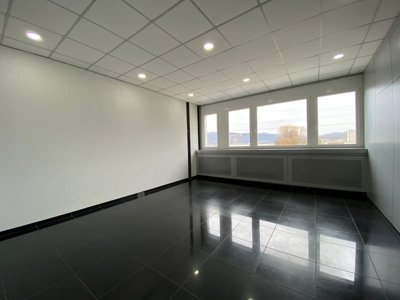 empty room, black tile floor, white walls, recessed lighting, large windows, bench under windows