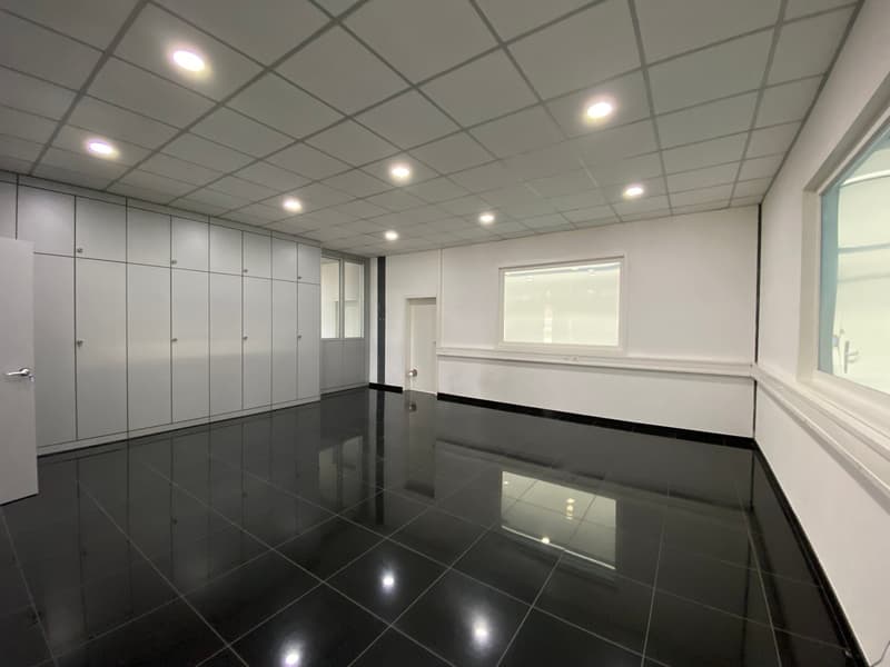 Empty room with white walls, black tiled floor, square windows, built-in cabinets, two doors, one open